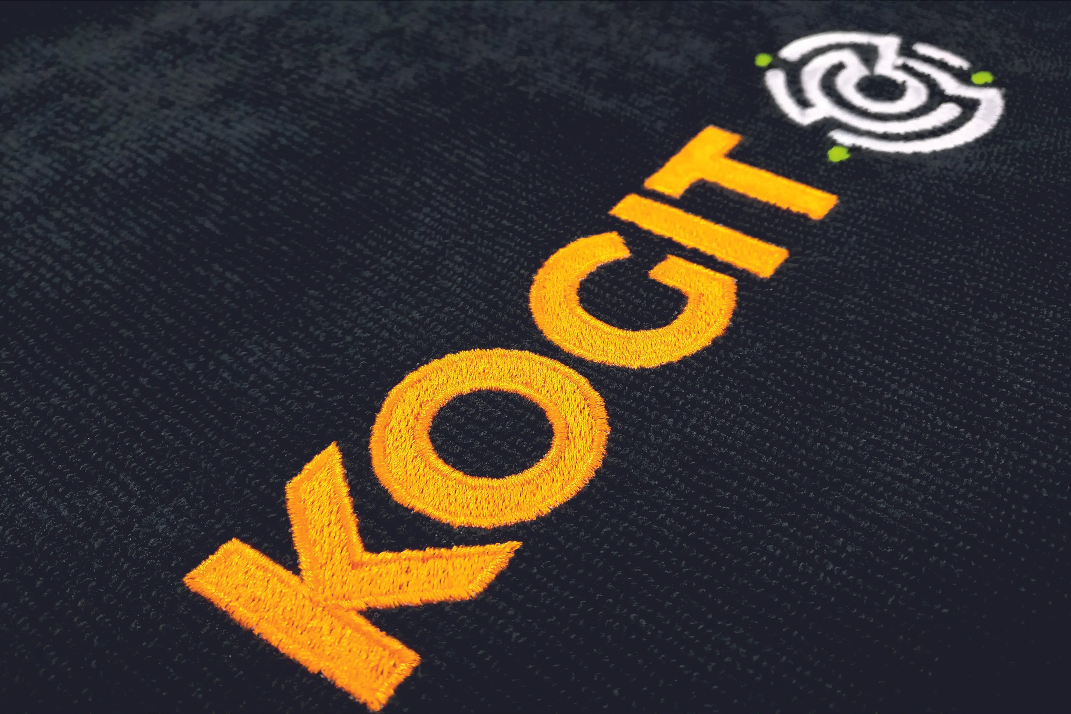 KOGIT logo in gelb auf schwarzem hintergrund bestickt