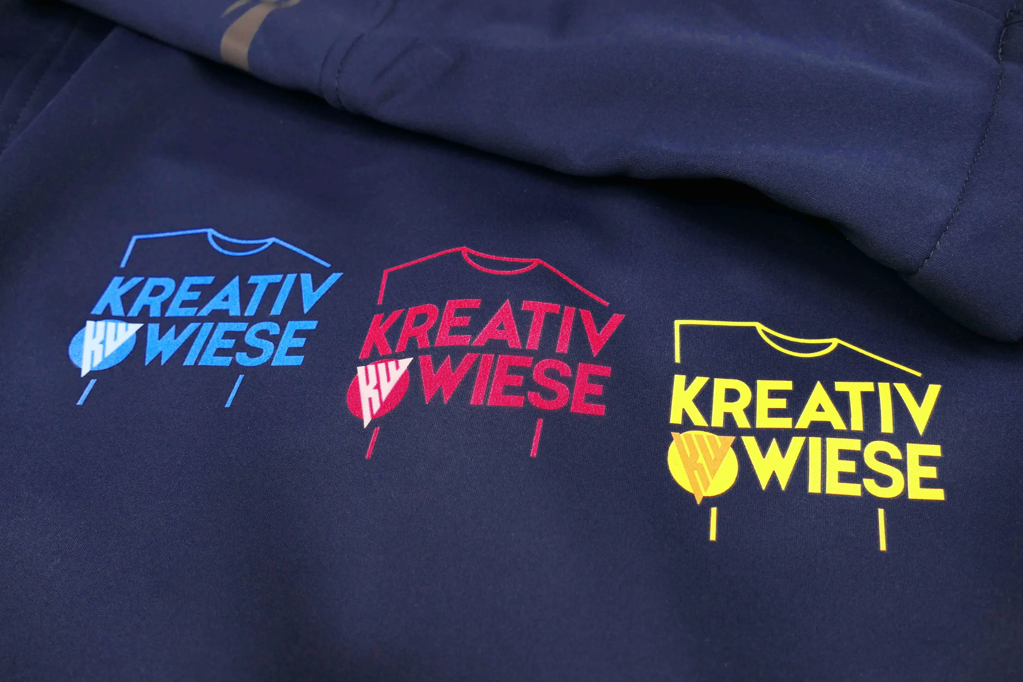 drei kreativwiese logos als aufdruck in blau rot und gelb